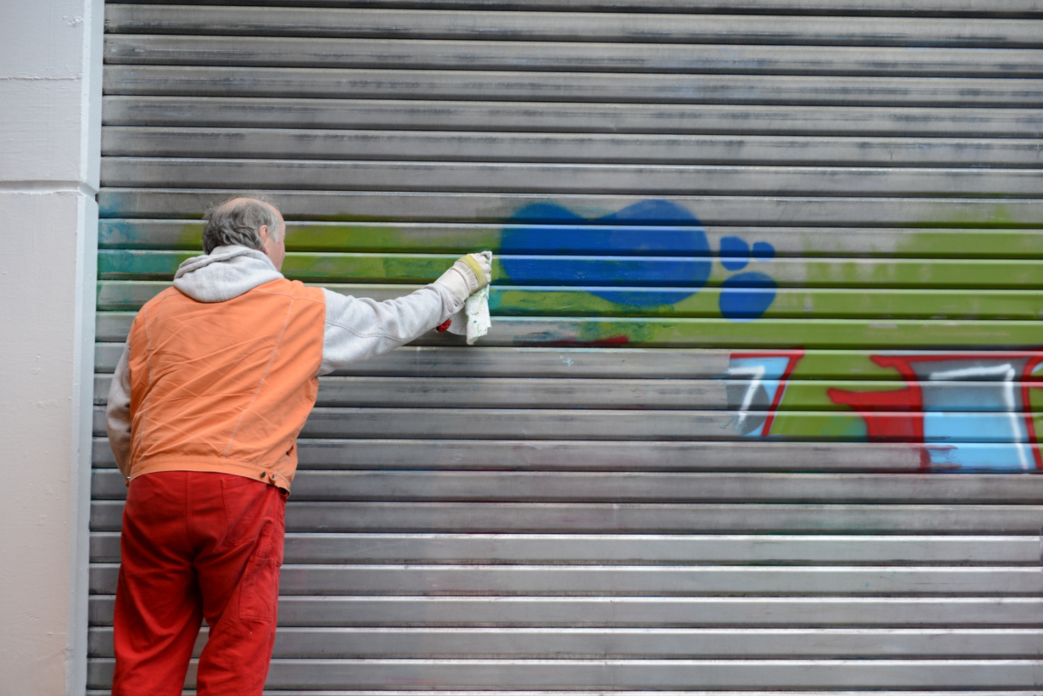 Mann entfernt Graffiti von Tor, Sachbeschädigung in Berlin, Aaden Detektei Berlin